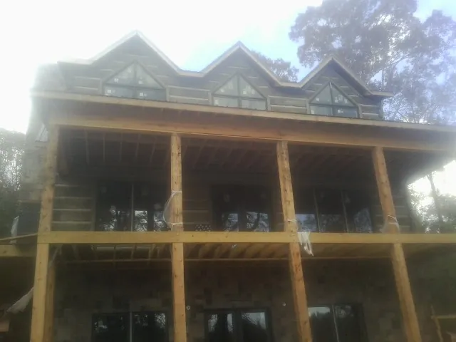 Dormers and porch framing on a large log home under construction — Roof Coating work by our crew in Jackson Springs