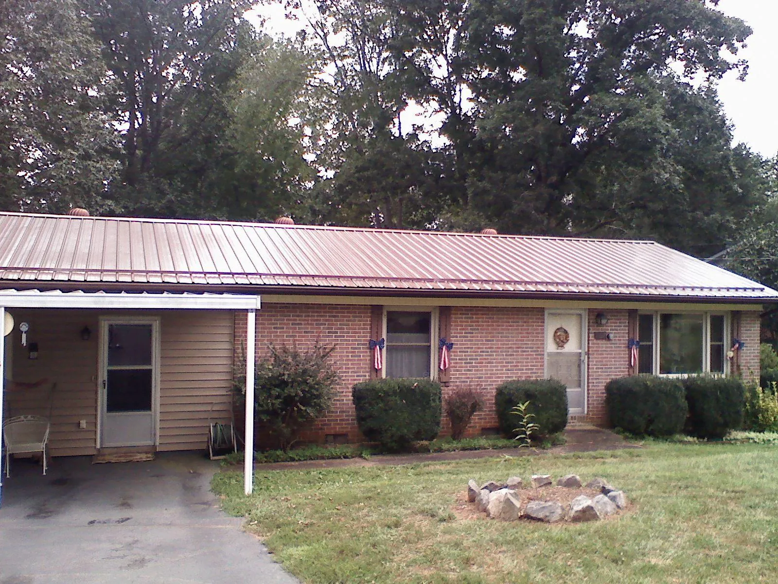 Bronze metal roof and carport on a brick ranch home — Roof Repair work by our crew in Jackson Springs