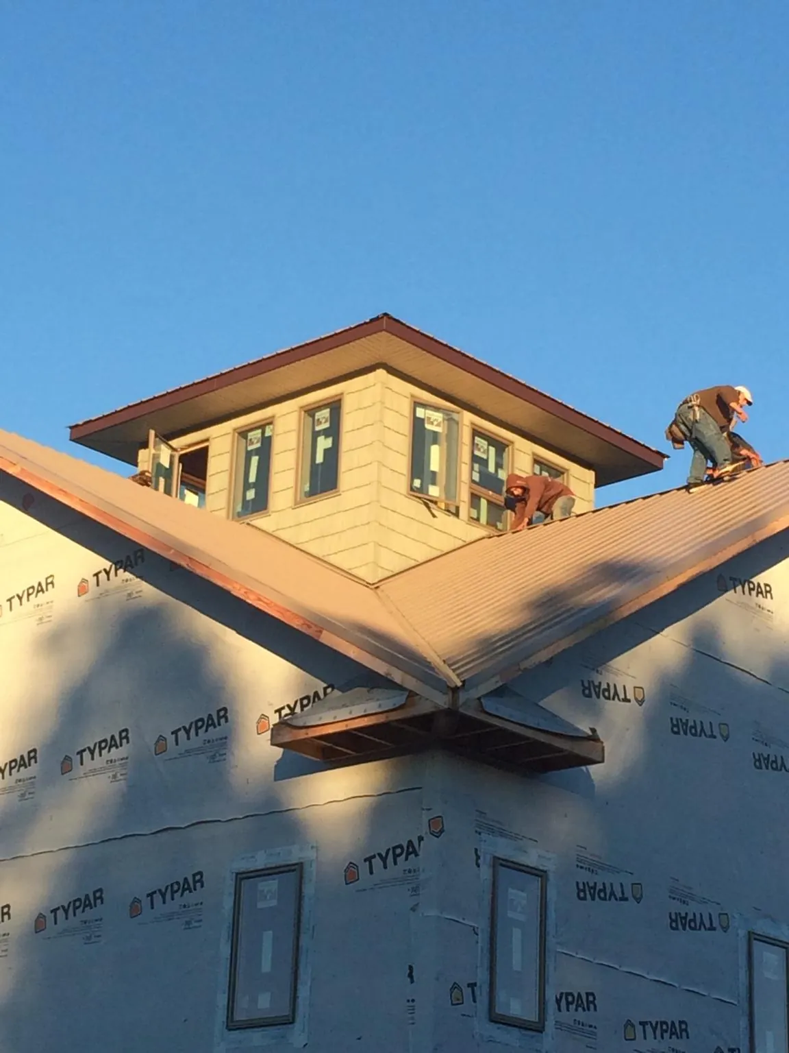 Roofers working around a rooftop cupola on a new metal roof at sunset — Roof Waterproofing in Jackson Springs by Roofing Brothers